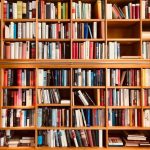 Brown wooden shelfs fully packed with books in a library